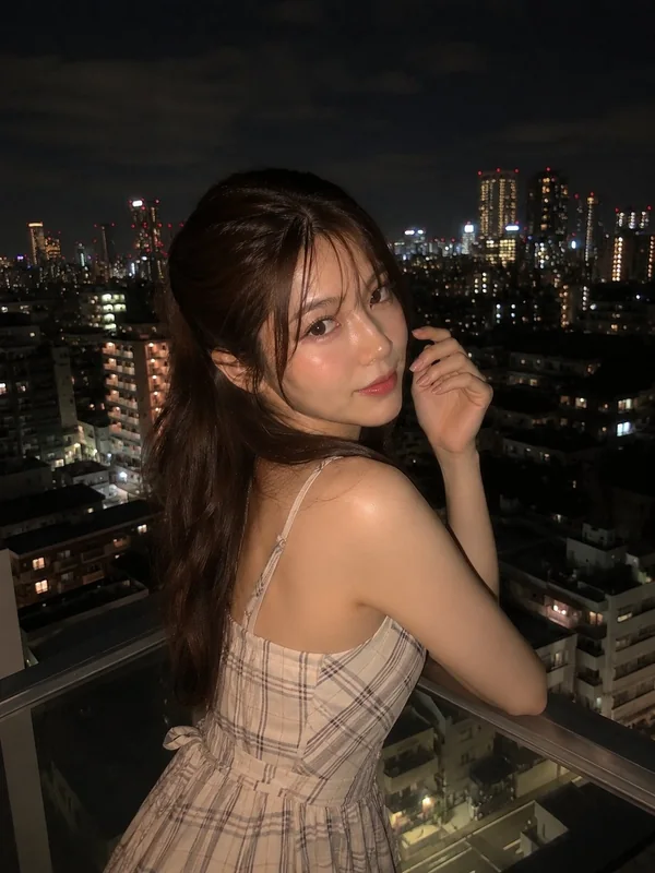 Adult-presenting fictional portrait for aipornfaceswap.com: woman in a checked dress on a city balcony at night